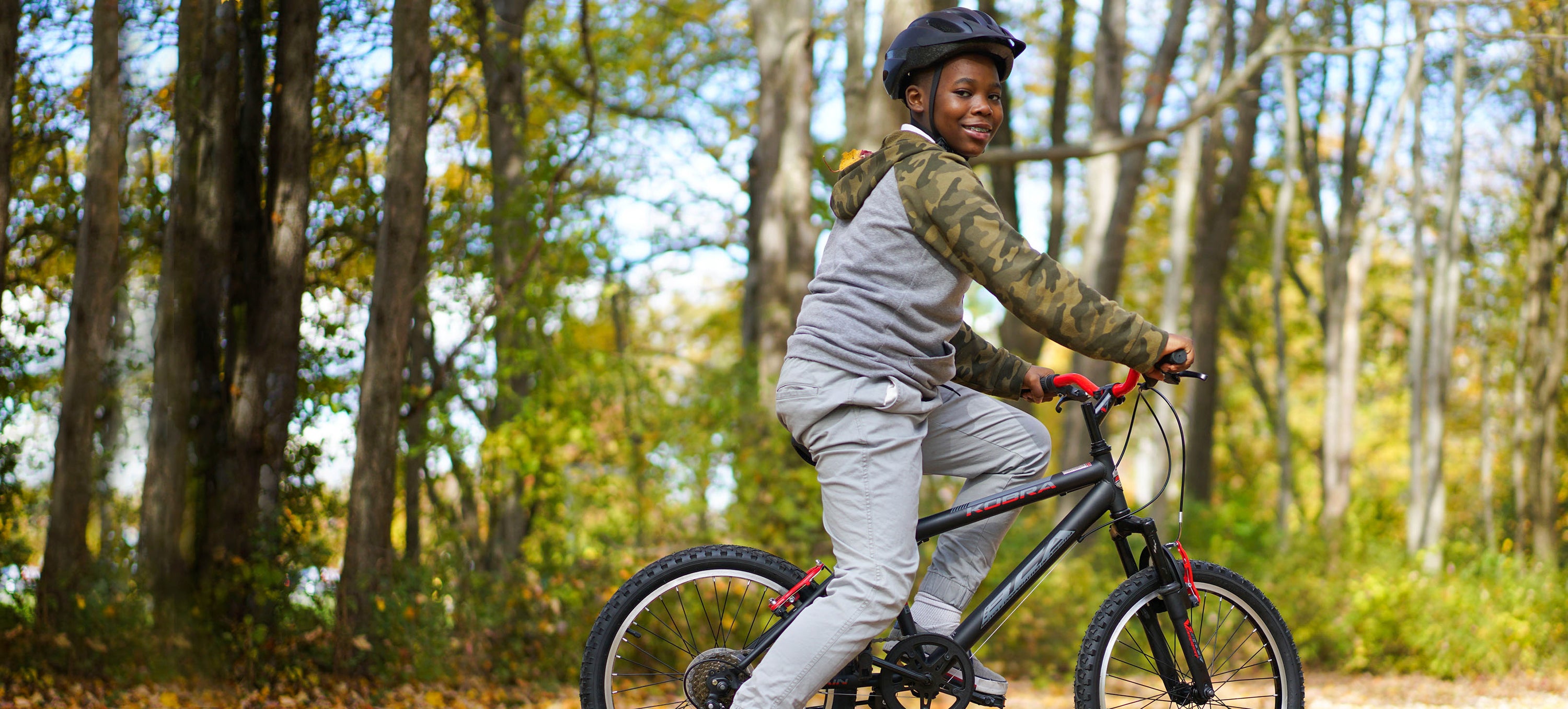 Young boy riding a black kobra in the woods